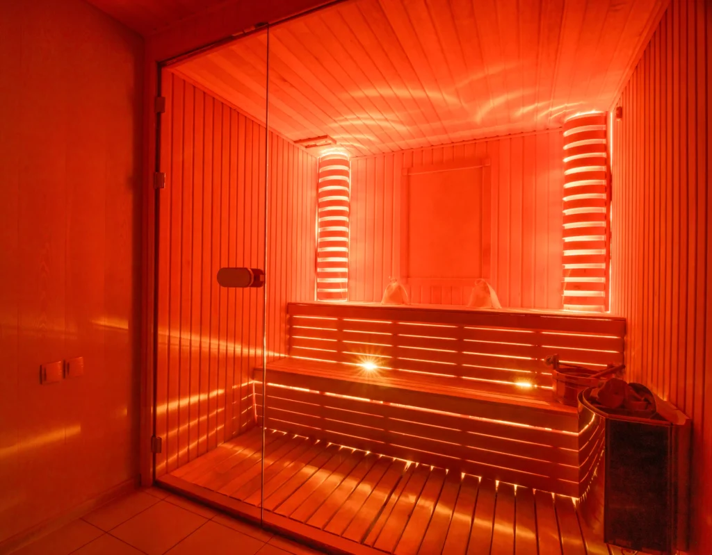 Elegant wooden infrared sauna interior with red light ambiance, professionally installed by Sauna Steam Center for luxury wellness spaces in South Florida.