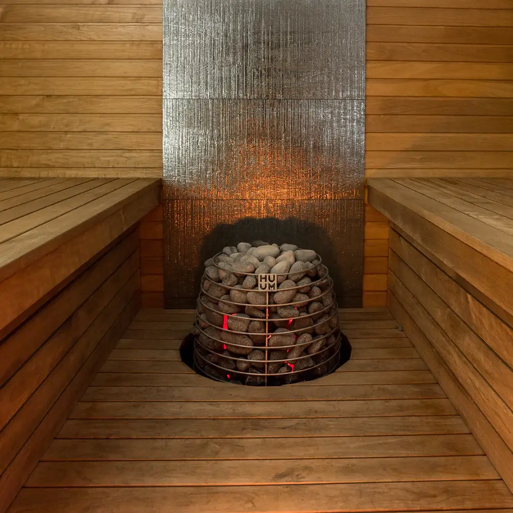 Sauna heater with hot stones inside a traditional sauna, showing the heat source used to warm the room and create steam for a comfortable home sauna experience.